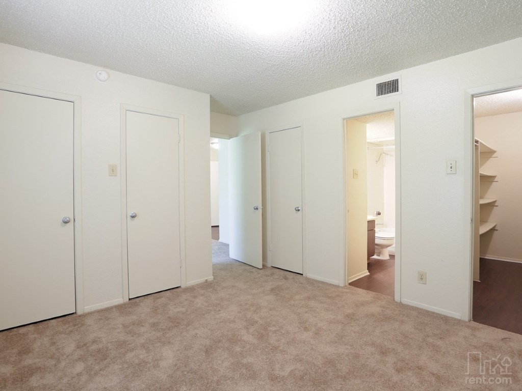 an empty living room with a carpeted floor and white closets