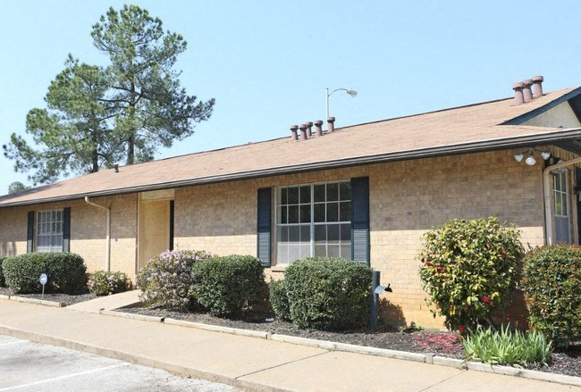 a brick building with bushes and a sidewalk