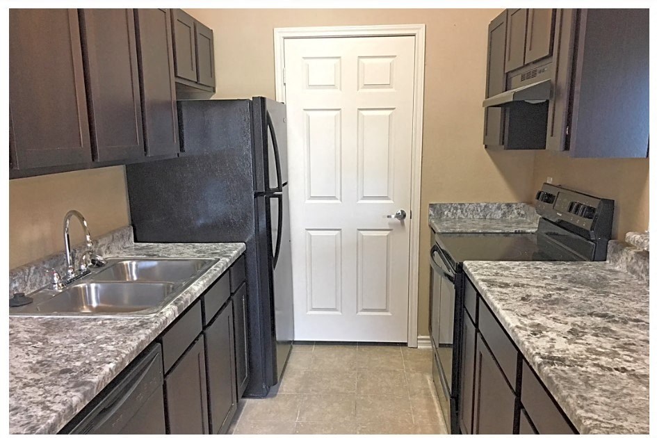 a kitchen with black cabinets and a white door