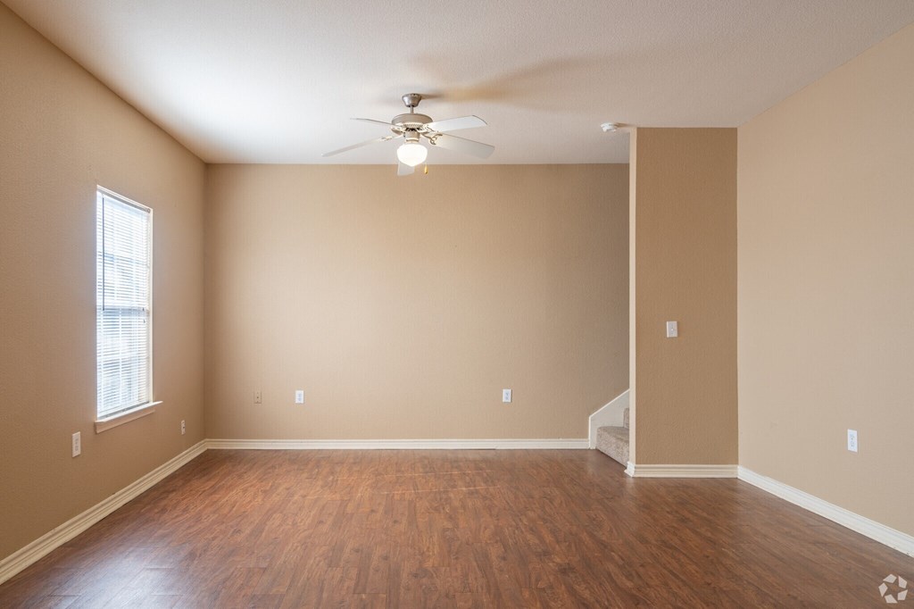 an empty living room with wood floors and a ceiling fan