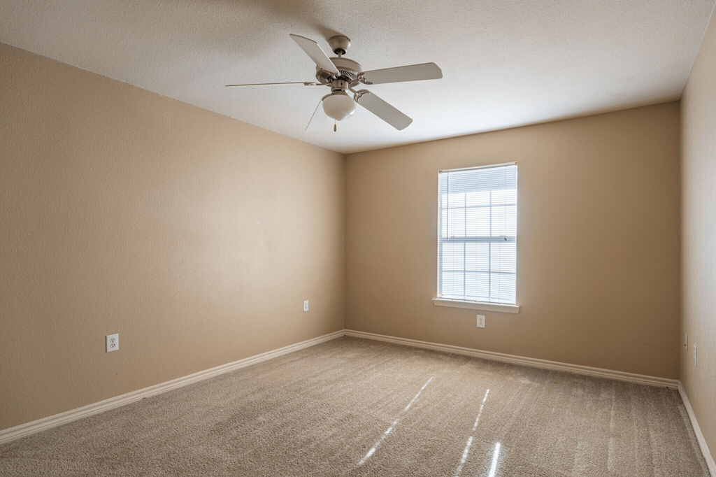 an empty room with a ceiling fan and a window