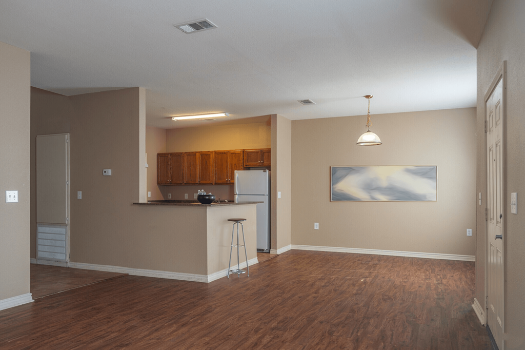 an empty living room and kitchen with a wood floor