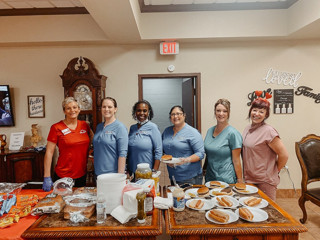 a group of women in blue t shirts stand in front of a table with food on it