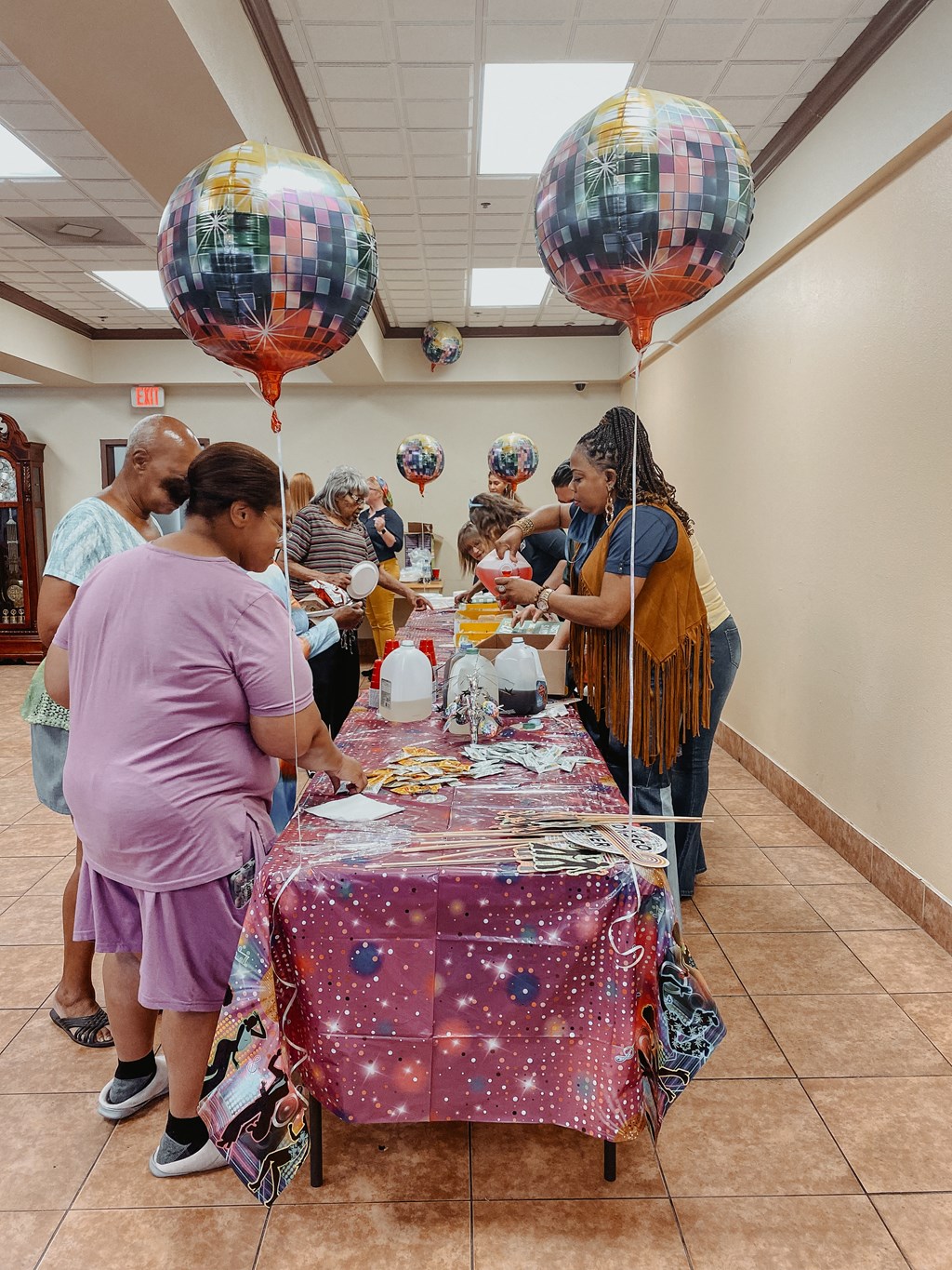 a group of people standing around a table with balloons