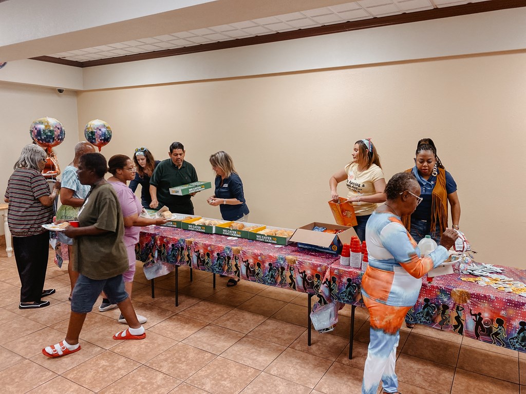 a group of people standing around a table with food on it