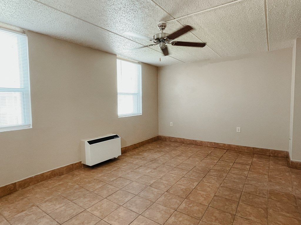 an empty room with a ceiling fan and a radiator