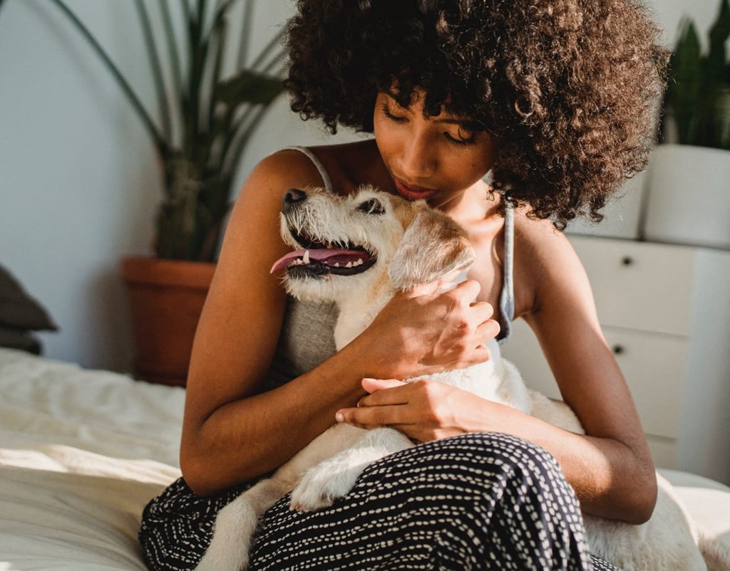 a woman sitting on a bed with her dog