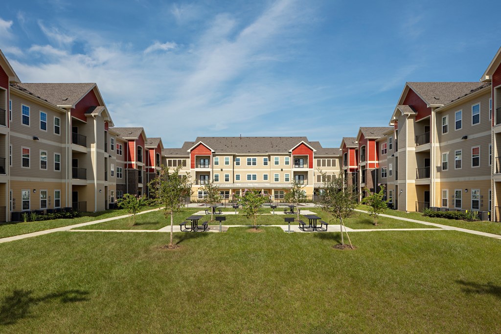 an outdoor courtyard with picnic tables in front of an apartment building