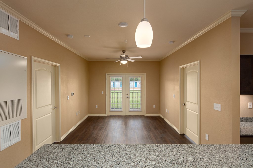 an empty living room with doors and a ceiling fan