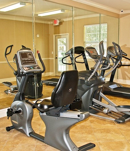 A gym with a treadmill, exercise bike and elliptical trainer.