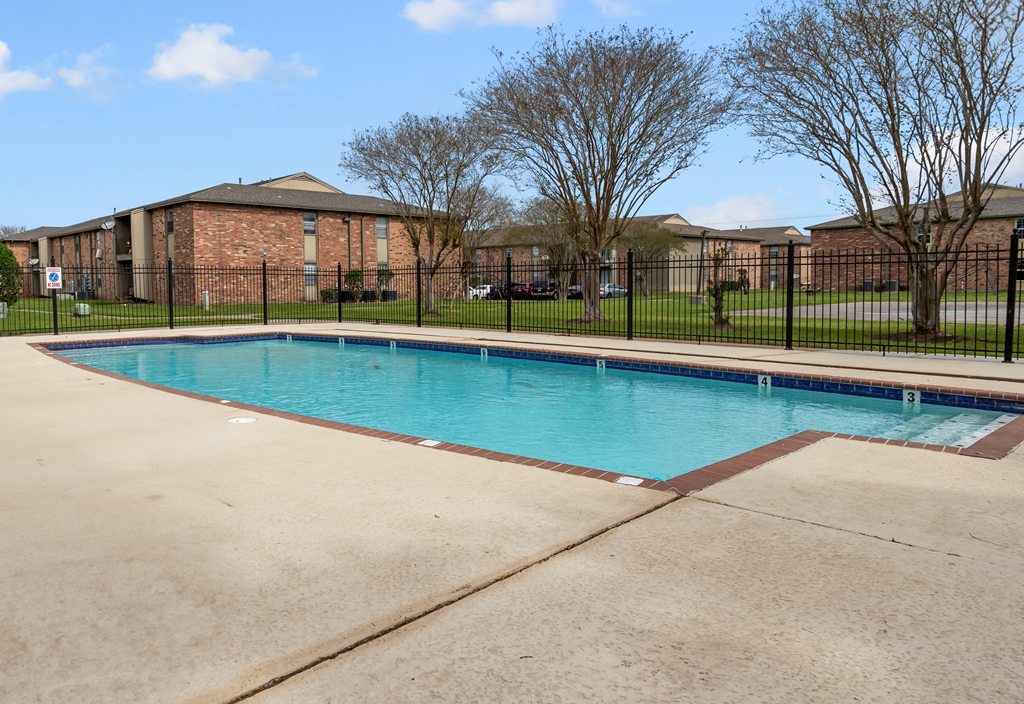 a swimming pool with a fence around it and a brick building in the background