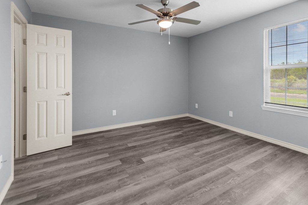 a bedroom with hardwood floors and a ceiling fan