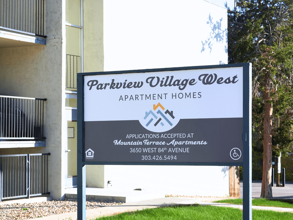 A sign for Parkview Village West Apartment Homes is displayed in front of a building.