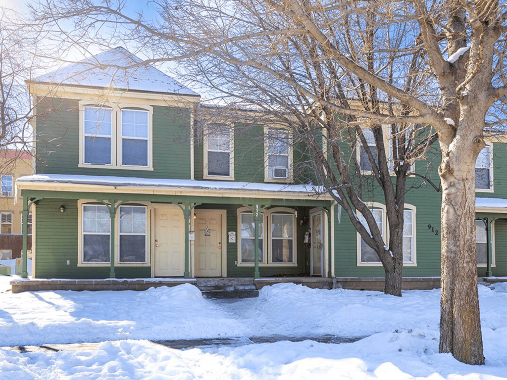 A green house with a tree in front of it.