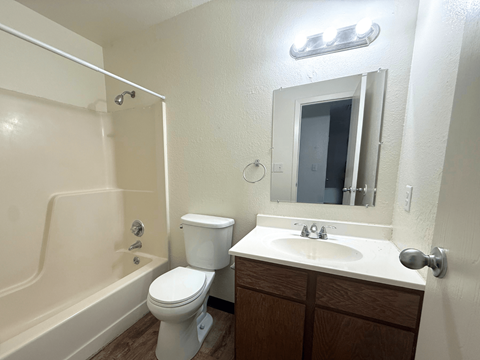 A white toilet sits next to a white sink in a small bathroom at Willow Grove Apartments, Clifton, Colorado, 81520.
