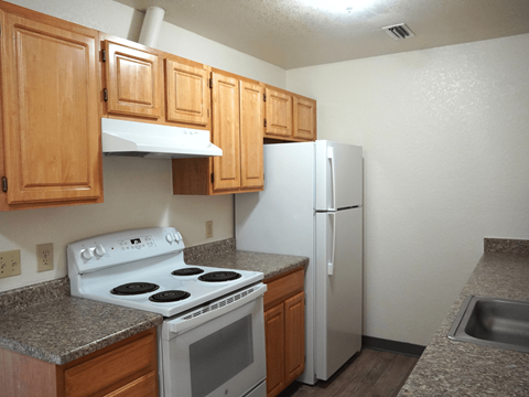 A kitchen with a white stove and refrigerator.