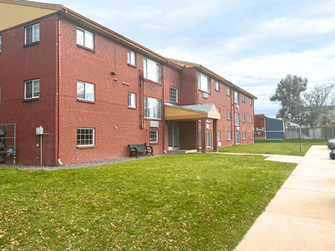 A red brick building with a green lawn in front.
