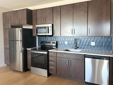 A kitchen with a stainless steel refrigerator, microwave, oven, and dishwasher.