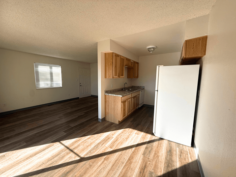 A kitchen with a white refrigerator and wooden floors.