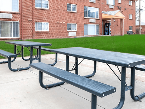 A black picnic table and bench in front of a brick building at Townview Plaza Apartments, Denver, CO.