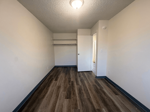 A room with wooden floors and white walls at Willow Grove Apartments, Clifton, Colorado.