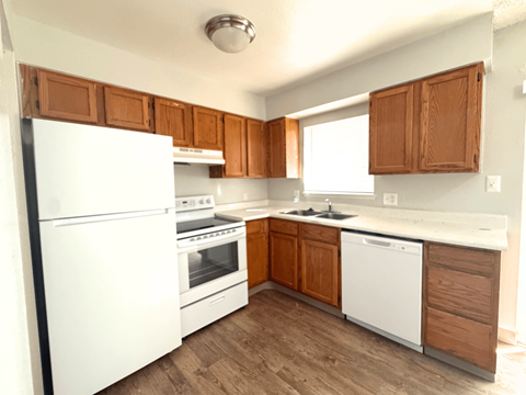A kitchen with white appliances and wooden cabinets.