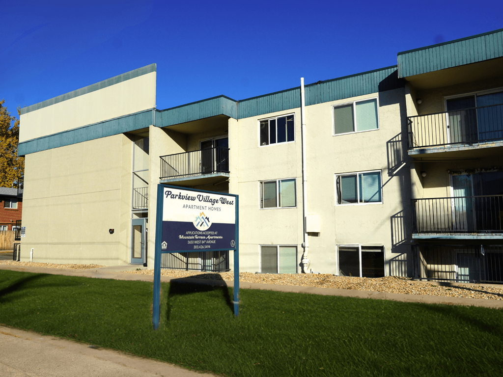 A sign in front of a building that says Parkview Village Apartments.