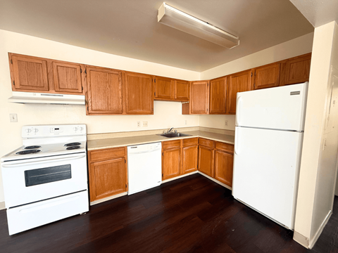 A kitchen with white appliances and wooden cabinets.