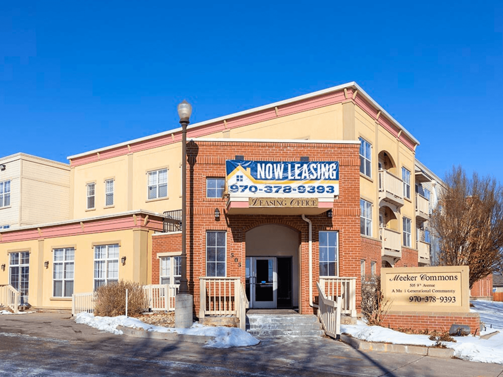 A building with a sign that says "NOW LEASING" on it.