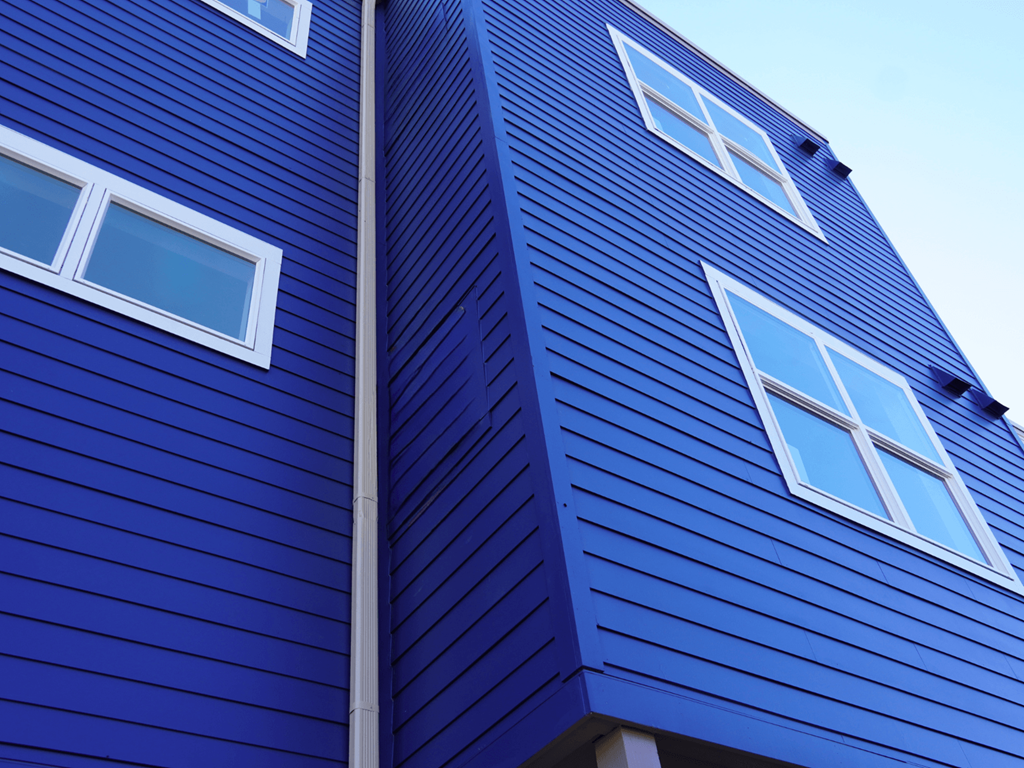 A blue wooden building with white windows.