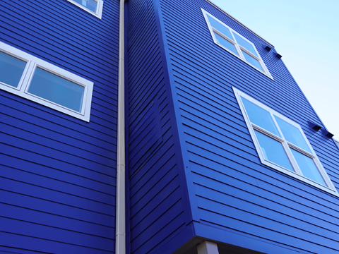 A blue wooden building with white windows at Gateway Village Apartments, Fort Morgan