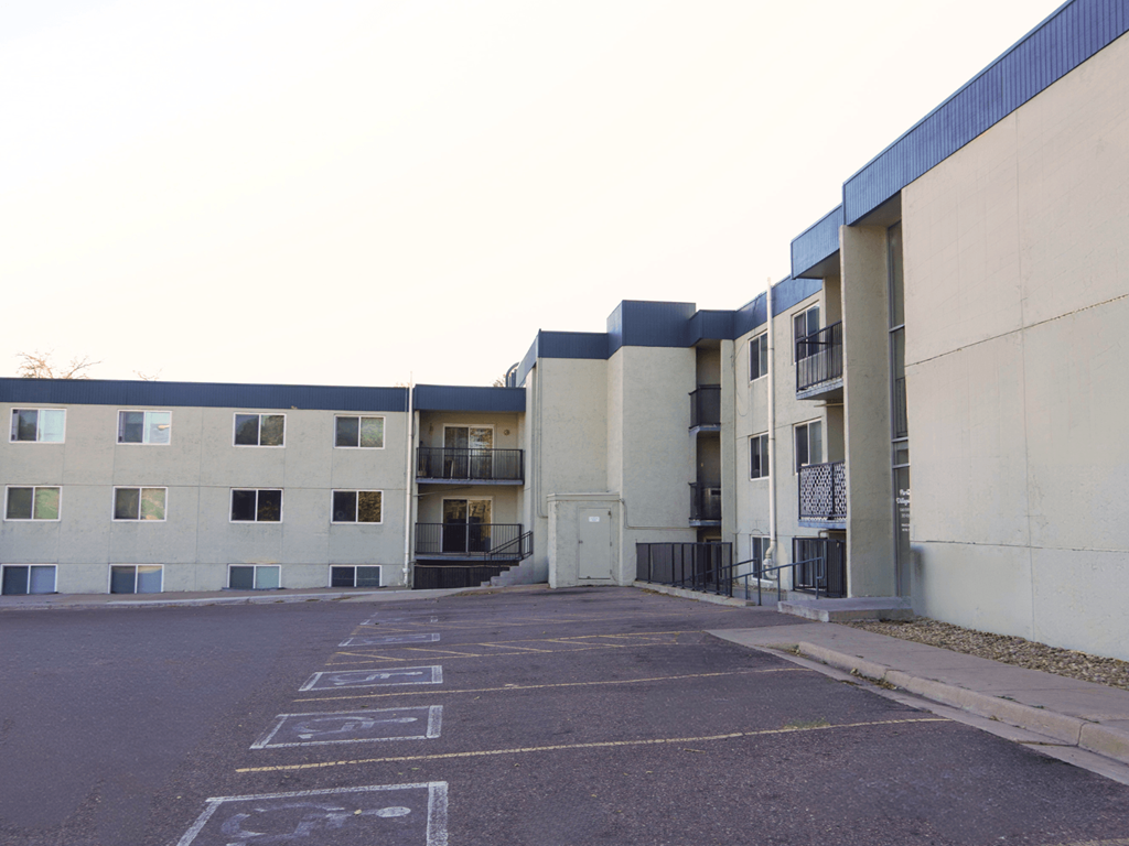 A parking lot in front of a building with a bicycle symbol painted on the pavement.
