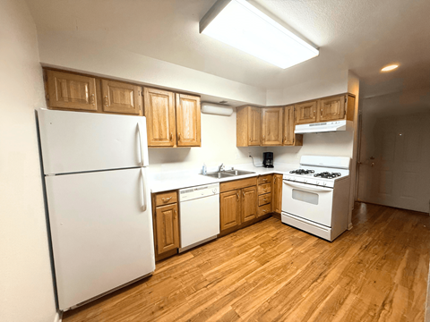 A kitchen with wooden cabinets and white appliances.