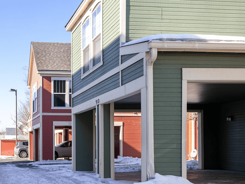 A green house with a red car parked in front.
