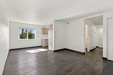 A large empty room with faux wood floors and white walls at Gateway Village Apartments in Fort Morgan, CO, 80701