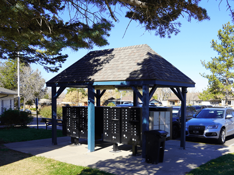 A gazebo with a roof and a signboard is surrounded by trees and a car is parked nearby at Mountain Terrace Apartments, Westminster, CO, 80031.