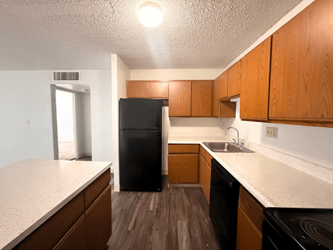 A kitchen with wooden cabinets and a black fridge.