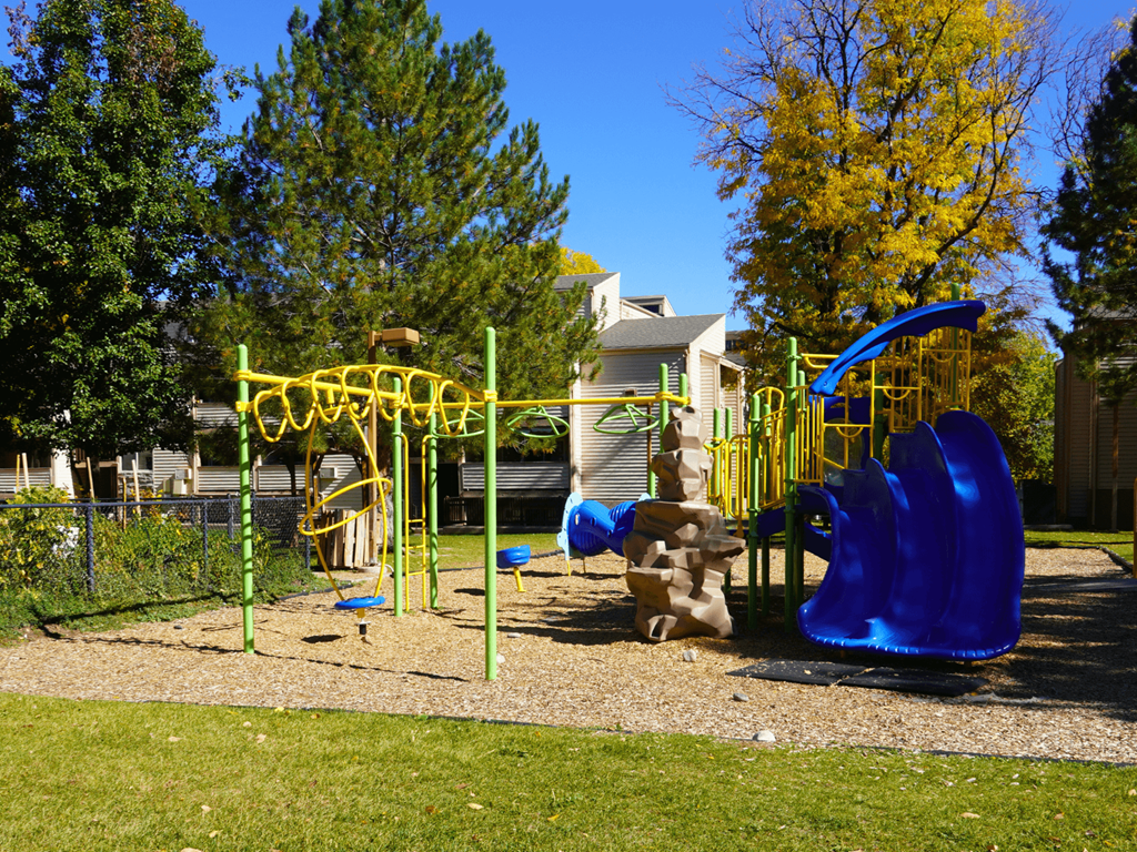 A playground with a blue slide and yellow equipment.
