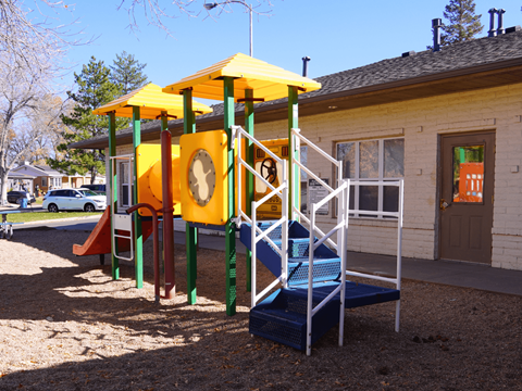 A playground with a yellow and green structure and a blue slide.