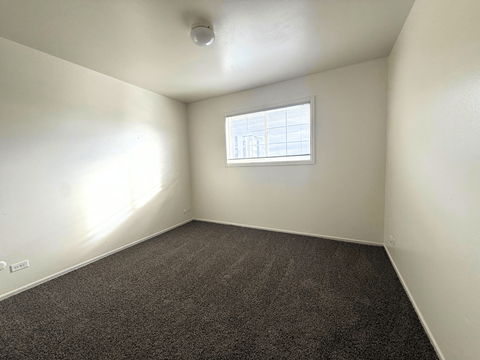 A room with a window and carpeted floor at Townview Plaza Apartments, Denver, CO.