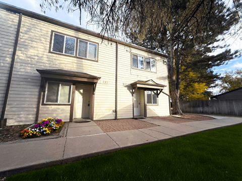 A beige house with a flower bed in front.