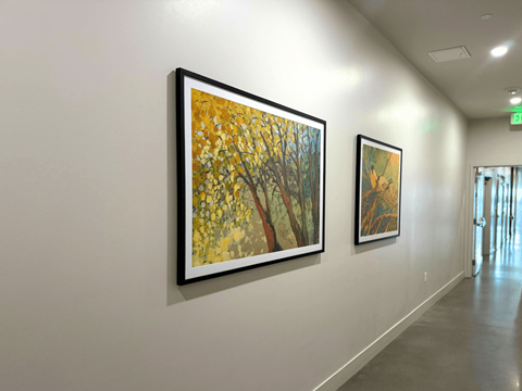 Two framed paintings of trees hang on a wall.