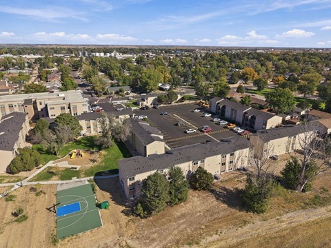 A bird's eye view of a residential area with apartment buildings, a swimming pool, and a parking lot at Gateway Village Apartments in Fort Morgan, CO, 80701