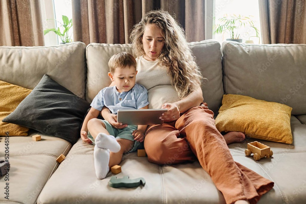young woman sitting on a couch with a boy using a tablet computer