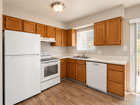 A kitchen with white appliances and wooden cabinets.
