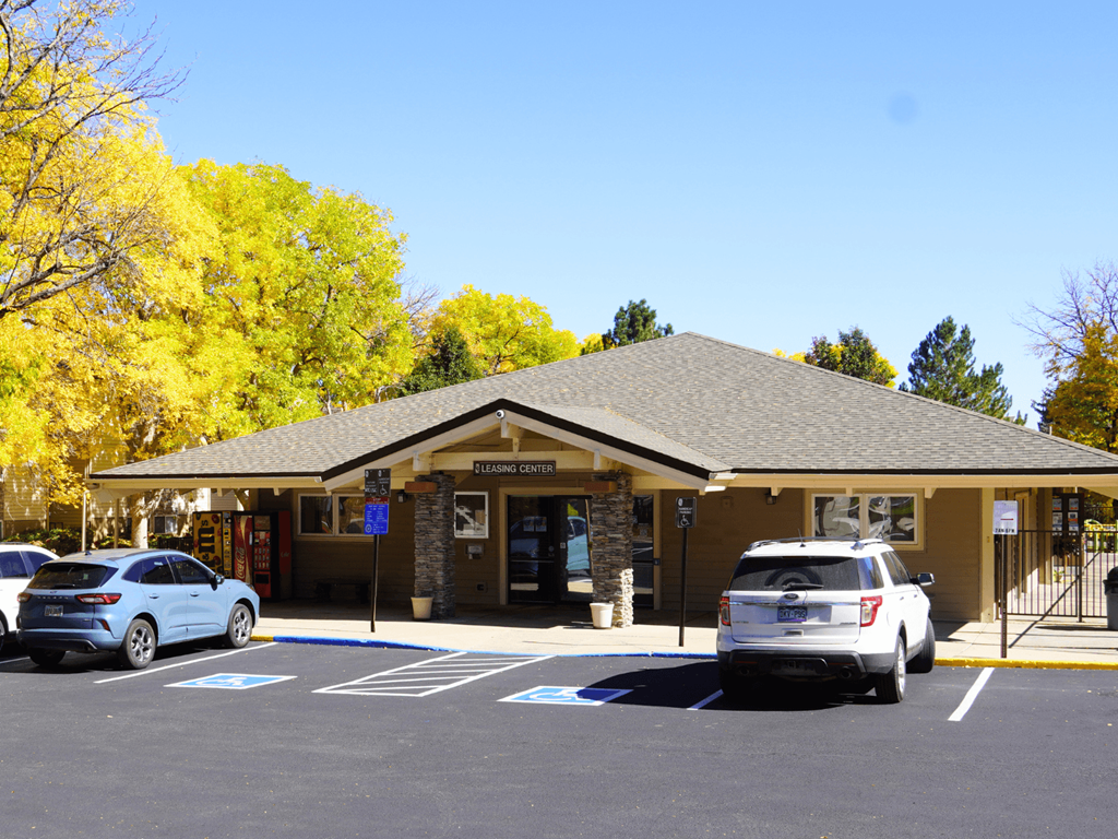 A car dealership with a white car and a silver car in front of it.