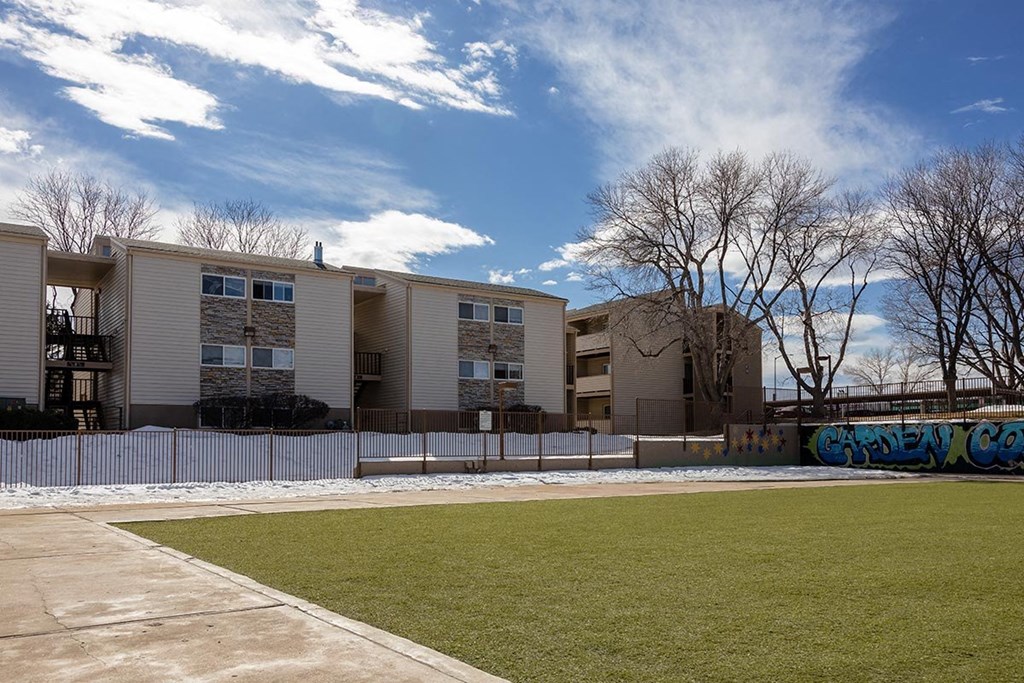 a large apartment complex with a grassy area in front of it at Garden Court, Denver, CO, 80220
