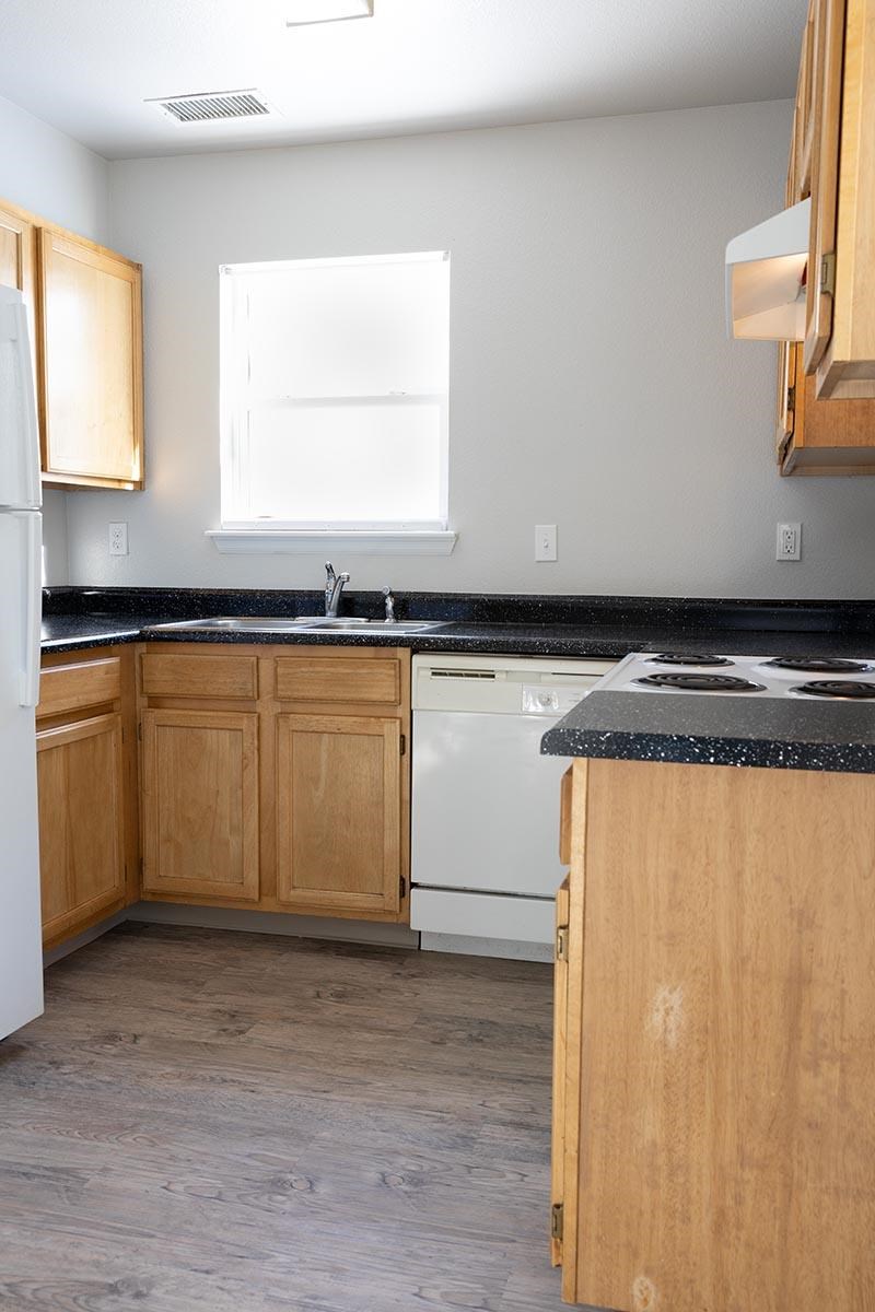 A kitchen with wooden cabinets and a black countertop at Meeker Commons, Greeley, CO, 80631