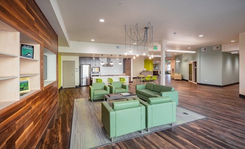 a lobby with green couches and chairs and a kitchen