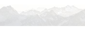 A mountain range covered in snow under a hazy sky.